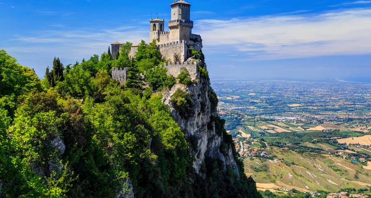 Vesting van San Marino bovenop een steile klif omringd door weelderig groen en uitgestrekte vlaktes eronder