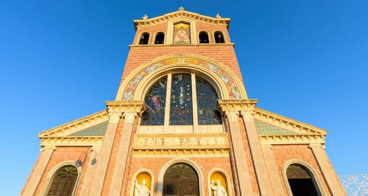 Gevel van een sierlijke basiliek met kleurrijke mozaïeken tegen een diepblauwe lucht.