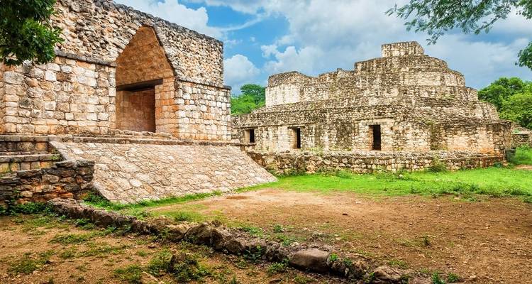 Alte Steinstrukturen der Mayastätten von Uxmal, umgeben von Grünflächen.