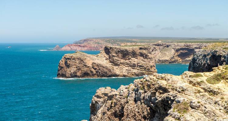 Des falaises côtières escarpées s'avançant dans l'Atlantique bleu profond avec des promontoires lointains le long d'un horizon dégagé