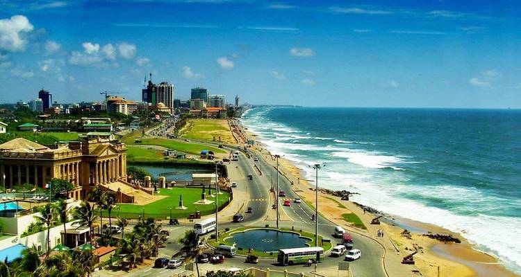 Vista aérea de la autopista costera de Colombo, parque junto al mar y olas rompiendo en una larga playa de arena.