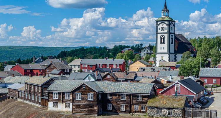 Traditional timber town with prominent white church tower under scattered clouds