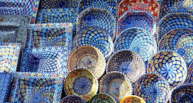 Exposition vibrante de plateaux et de bols en céramique tunisienne peints à la main dans un marché.