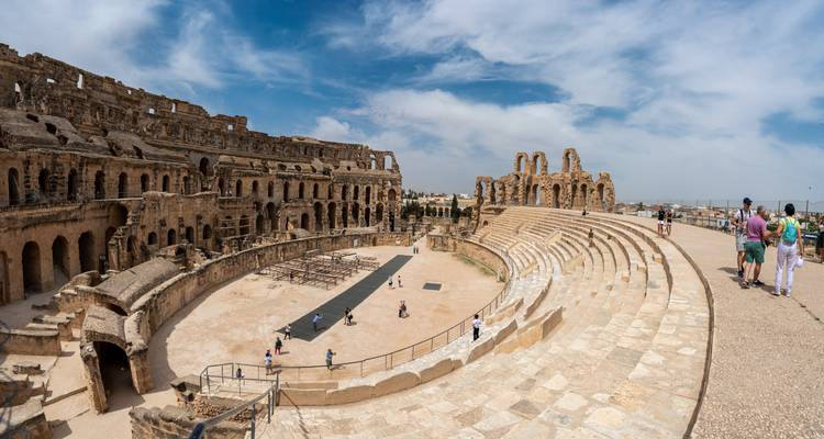 Vaste intérieur panoramique de l'amphithéâtre d'El Jem avec des touristes explorant les gradins antiques.