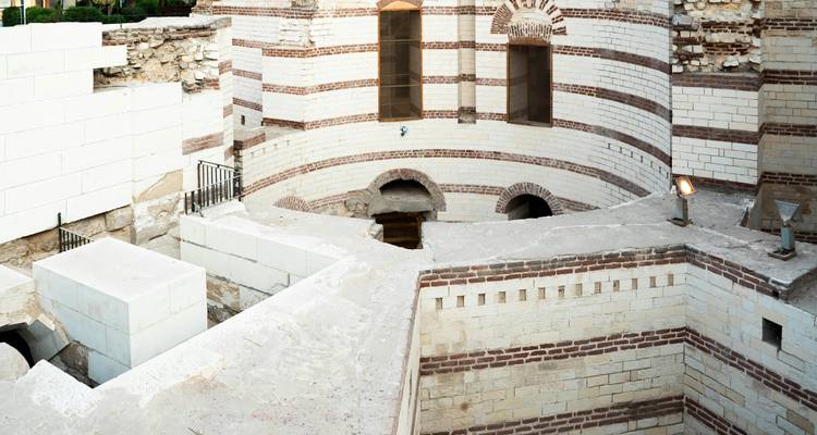 Vue rapprochée des murs de pierre à rayures blanches et rouges et des fenêtres cintrées d'un site copte ancien.