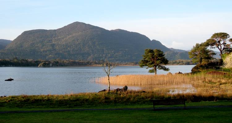 Lac paisible bordé de roseaux et dominé par un impressionnant décor montagneux dans le parc national de Killarney.