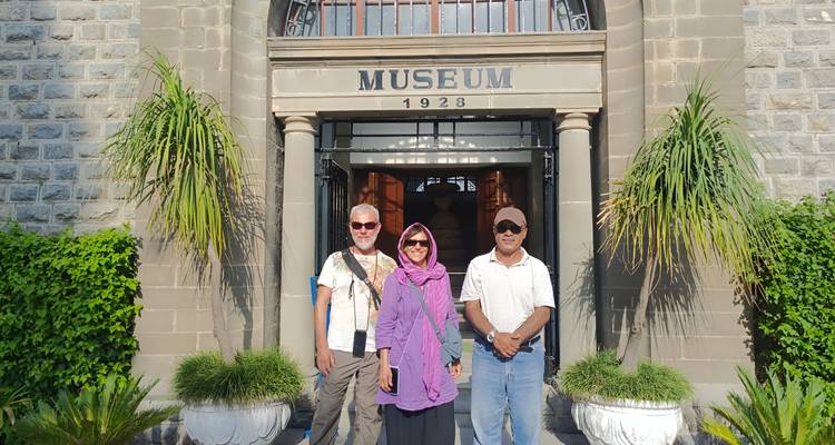 Three tourists posing in front of the grand entrance of a historic museum building