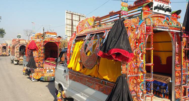 Brightly painted Pakistani trucks lined up along a street under clear blue skies
