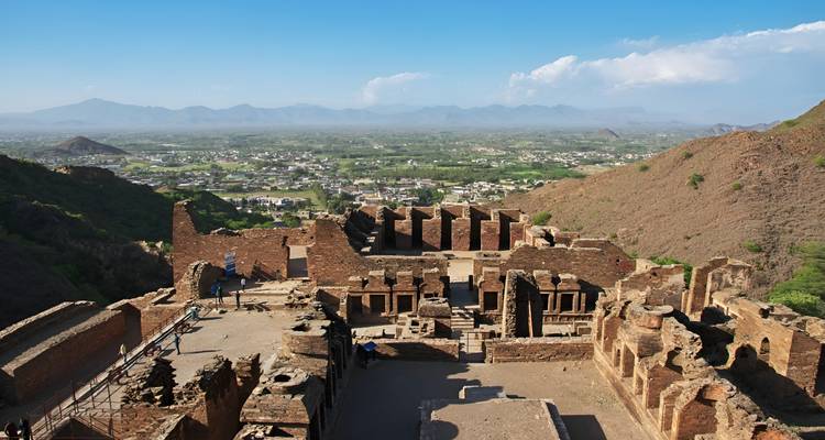 Panoramic ruins atop a ridge with expansive views of a green plain and distant mountains