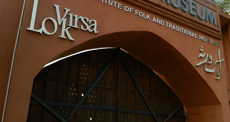 Entrance arch of Lok Virsa Museum displaying bold lettering on an orange wall