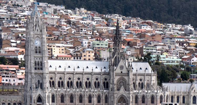 Nahaufnahme der gotischen Fassade der Basilica del Voto Nacional mit Häusern von Quito, die den Hügel hinunterkaskadieren