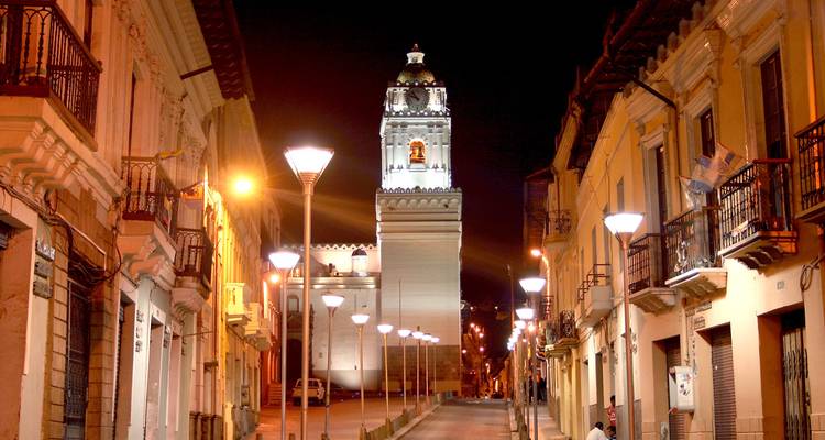 Illuminierter kolonialer Glockenturm und beleuchtete Fußgängerstraße in Quito bei Nacht