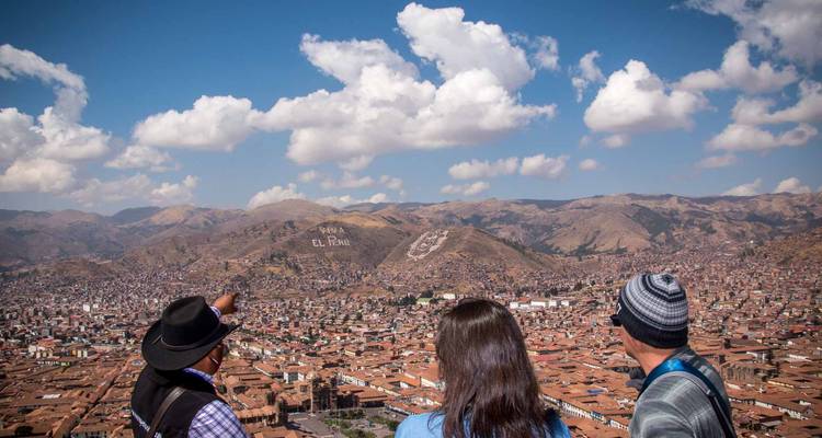 El guía señala la vista panorámica del valle de Cusco y las montañas desde un mirador elevado.