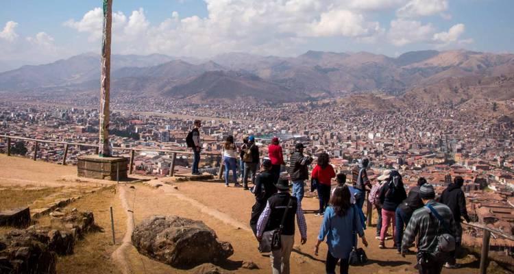 El grupo de turismo se reúne en la barandilla de la cima de la colina con vistas a la extensa ciudad de Cusco.