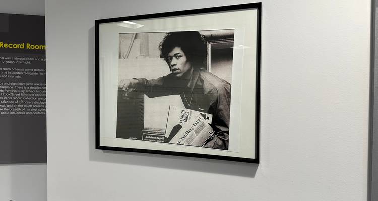 Ingelijste zwart-witfoto van een musicus uitgestald op een eenvoudige galerijmuur.