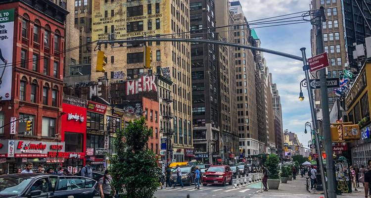 Rue animée de Manhattan bordée de grands immeubles, de trafic et de piétons.