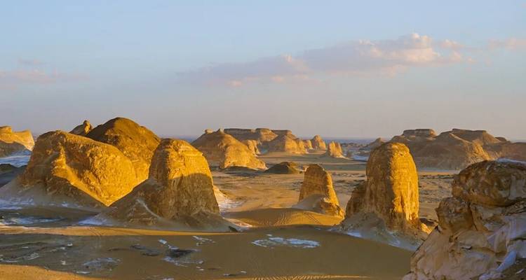 Paisaje desértico iluminado por el oro con pilares de arenisca agrupados y valles arenosos planos