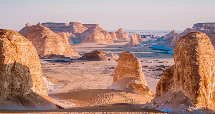 Valle desértico colorido enmarcado por altas torres de roca erosionada bajo un cielo despejado