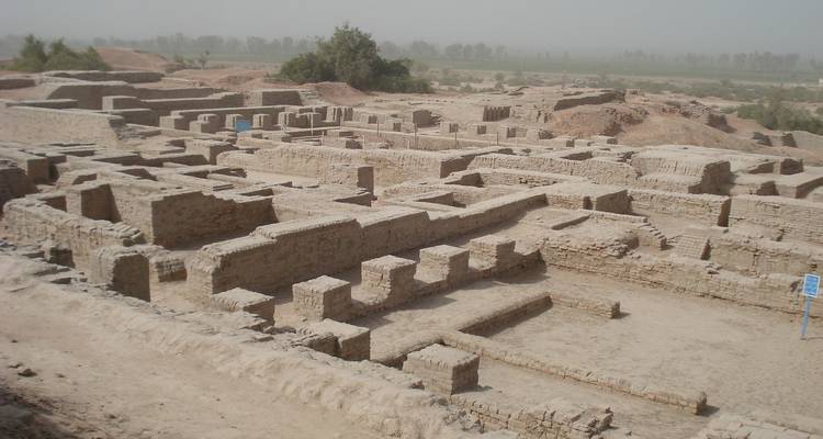 Wide view of excavated ancient brick foundations of a settlement site under hazy skies.