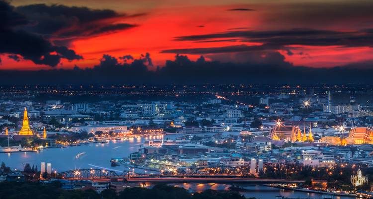 Panoramisch avondlicht uitzicht op de Bangkok skyline langs de Chao Phraya rivier met een vurig rode zonsondergang.