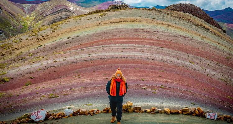 Reiziger die voor de indrukwekkende gestreepte lagen van Peru's Rainbow Mountain uitkijkt.