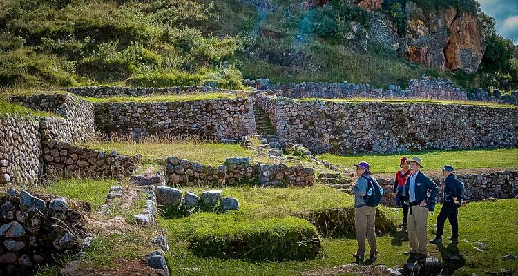 Drie wandelaars die naar de stenen terrassen van een oud Inca-archeologisch gebied kijken.