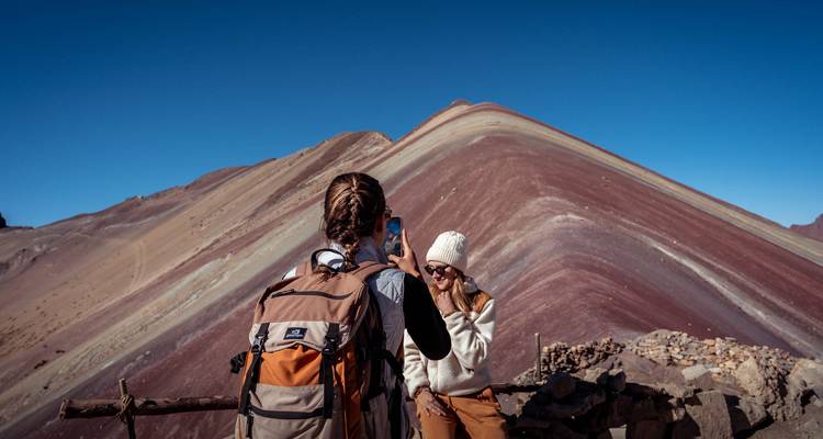 Een reiziger fotografeert haar vriendin tegen de kleurrijke lagen van Peru's Regenboogberg.