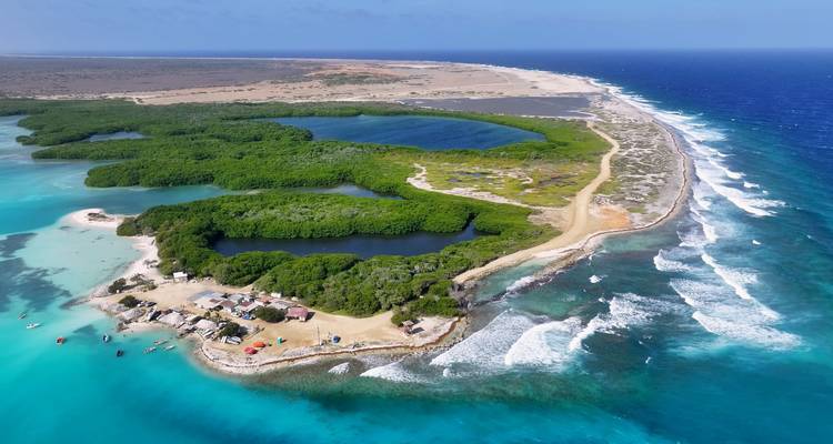 Vue aérienne d'une île étroite des Caraïbes avec des lagons turquoise, des palétuviers et l'océan environnant bordé de récifs.