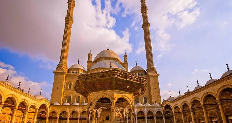 Grote moskee met grote koepels en dubbele minaretten omlijst door een sierlijke binnenplaats onder warme hemels.