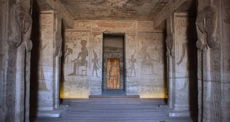 Interieur hal van Abu Simbel met hiëroglyfische muren, uitgehouwen zuilen en een deuropening verlicht door zacht licht