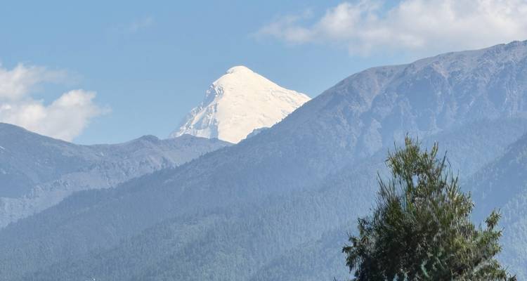 Sneeuwbedekte Himalaya-top die op een heldere dag boven de beboste lagere bergketens uittorent