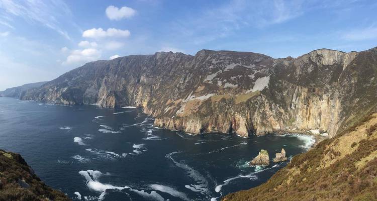 Les imposantes falaises marines de Slieve League plongeant dans les eaux bleu profond de l'Atlantique avec des motifs d'écume tourbillonnante.