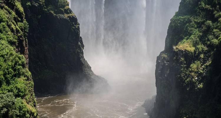 Une puissante cascade se jette dans un étroit canyon rempli de brume et d'embruns.