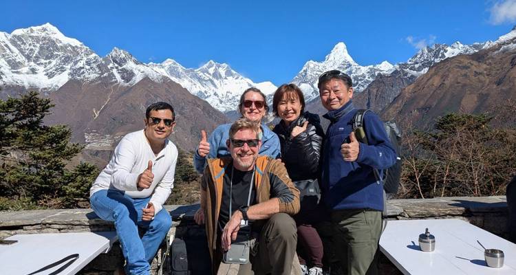 Trekkinggangers geven een duim omhoog met de besneeuwde toppen van de Everest-regio als schitterend decor op de achtergrond.