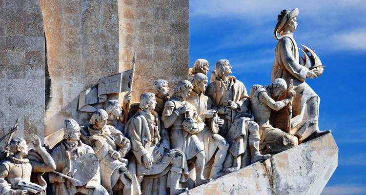 Gros plan des statues en marbre du Monument aux Découvertes de Lisbonne sur un ciel bleu éclatant.