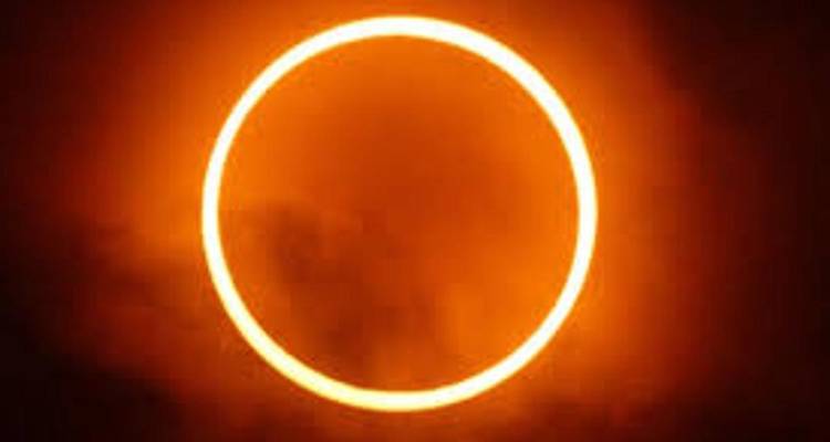 Felgele oranje ring van een ringvormige zonsverduistering tegen een donkere lucht.