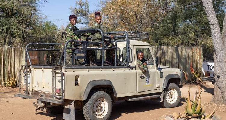 Los guardabosques se paran en la parte trasera de una Land Rover beige listos para una patrulla