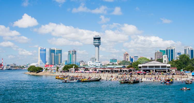 El moderno skyline de Dar es Salaam se eleva detrás de un bullicioso paseo marítimo y una playa abarrotada