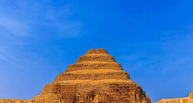 La Pirámide Escalonada de Djoser elevándose contra un cielo azul vibrante con andamios de restauración en su base.