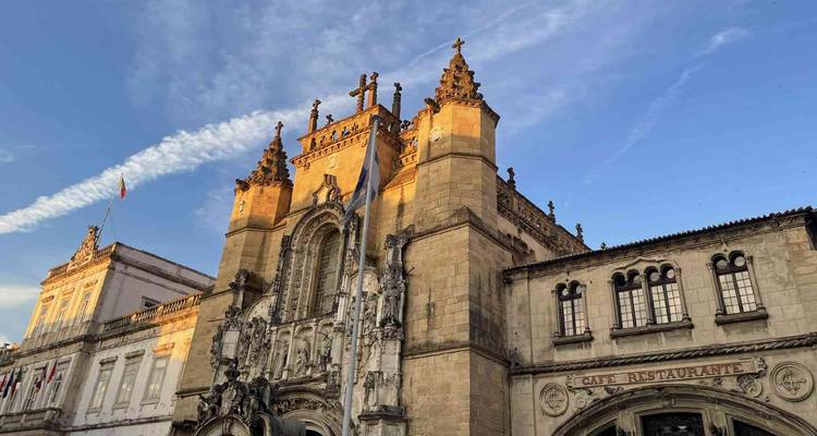 La façade d'une église gothique brille à la lumière déclinante du jour sous une traînée de nuages à Coimbra.