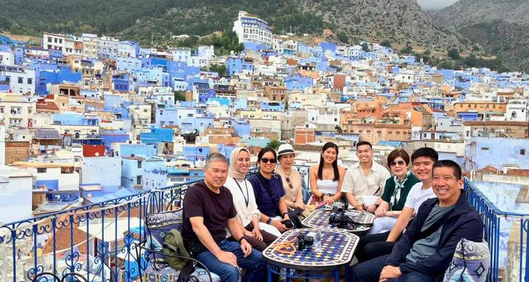 Le groupe est assis à une terrasse sur le toit d'un café qui surplombe la médina bleue de Chefchaouen étendue sur le flanc de la colline.