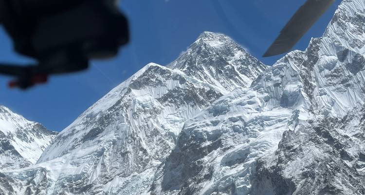 Rotsachtig Everest-massief bekeken vanuit een helikoptercockpit met zichtbare rotorbladen.