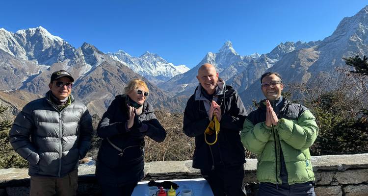 Groep van wandelaars geven elkaar een hand ter begroeting terwijl ze voor het dramatische Himalaya-landschap staan.