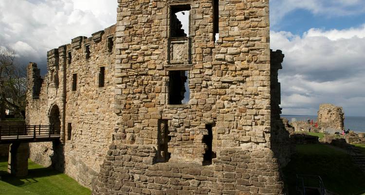 Ruines de pierre d'un château côtier médiéval sous un ciel partiellement nuageux