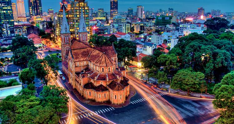 Long-exposure twilight shot of Notre-Dame Cathedral of Saigon surrounded by city light trails