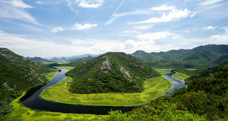 Spectaculaire hoefijzerbocht van een kronkelende rivier tussen weelderig groene heuvels onder een heldere lucht.