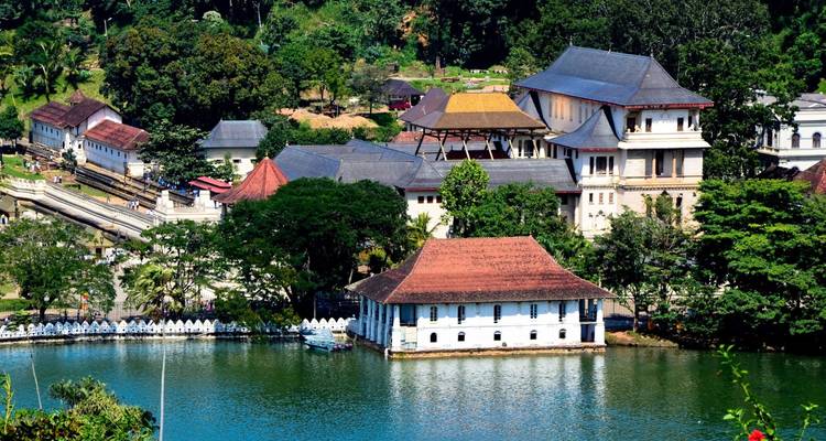 Vue sur le lac de Kandy vers le temple et les bâtiments de la ville entourés de verdure.