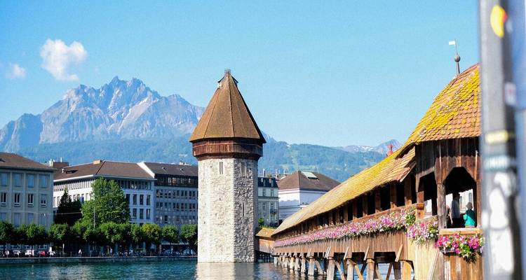 Le pont de la Chapelle, emblématique, et la Tour de l'Eau se reflétant dans le lac de Lucerne avec un arrière-plan alpin.