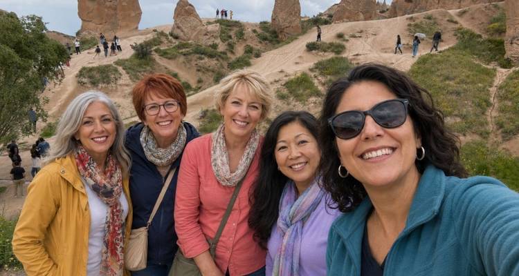 Een groep lachende vrouwen poseert voor een selfie tussen de unieke rotsformaties van Cappadocië, terwijl andere bezoekers op de achtergrond rondkijken.