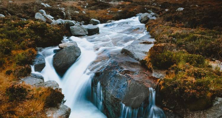 Ruisseau lisse à pose longue se précipitant sur les rochers dans une vallée de lande.